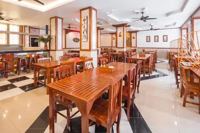 a restaurant with wooden tables and chairs at Sunshine Patong in Patong Beach