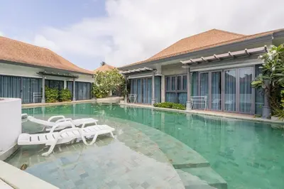 a swimming pool with two lounge chairs in a building at Tajh Pool Villas in Chalong