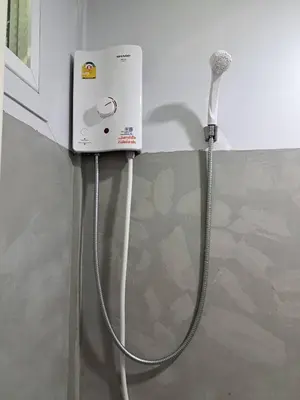 a washing machine with a hose attached to a wall at Hunny Home in Ko Yao Noi