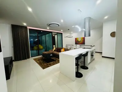 a kitchen and living room with a table and a couch at Sunrise Villa 21 in Phuket Town