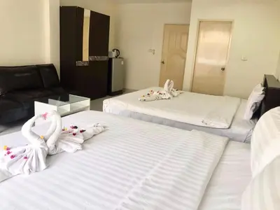 two beds with white towels on them in a room at Kata Beach Guesthouse in Kata Beach