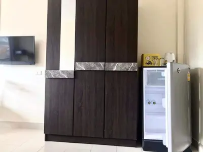 a small kitchen with a refrigerator next to a wall at Kata Beach Guesthouse in Kata Beach