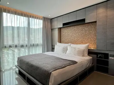 a bedroom with a bed and a large window at Kamala Beach P72 Exclusive Junior Suite in Phuket Town
