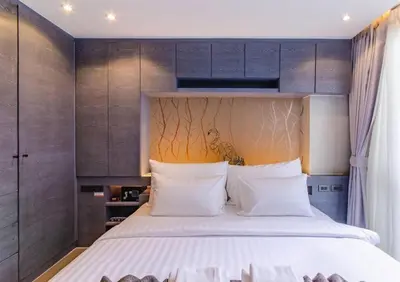 a bedroom with a large bed and wooden cabinets at Kamala Beach P72 Exclusive Junior Suite in Phuket Town