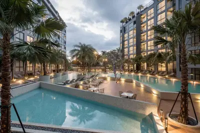 a large swimming pool with palm trees and buildings at Kamala Beach P72 Exclusive Junior Suite in Phuket Town