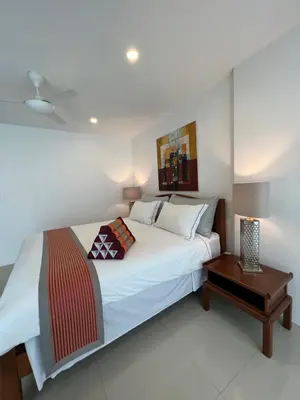 a bedroom with a large white bed and a table at Super Som Rawai in Rawai Beach
