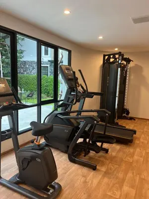 a gym with a treadmill and elliptical machines and windows at Seaside vacation in Rawai Beach