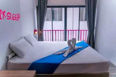 a bed with a towel on it in front of a window at Slumber Surf Phuket Kata in Kata Beach