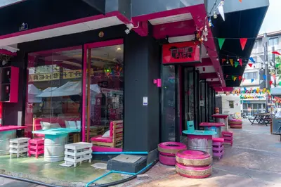 a store with pink and purple tables and stools outside at Slumber Surf Phuket Kata in Kata Beach