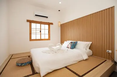 a bedroom with a large white bed with a wooden headboard at Villa Sunrise Garden A180 in Thalang