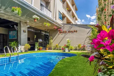 a swimming pool in the yard of a building with flowers at Noble House Patong in Patong Beach