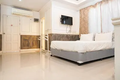 a bedroom with a bed and a tv on a wall at Guesthouse Phuket Airport in Ban Bo Han