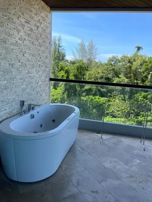 a white bath tub in a room with a large window at The Regent Bangtao Apartments in Bang Tao Beach