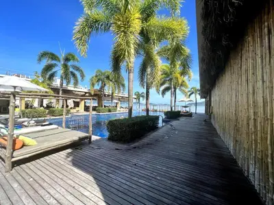 a wooden walkway next to a pool with palm trees at Spectacular Ocean View Apartment in Ban Saiyuan (1)