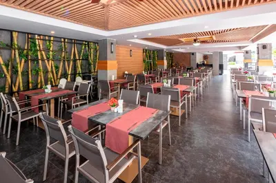 a restaurant with tables and chairs and plants at Tuana Hotels Casa Del Sol in Kata Beach