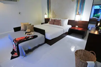 a hotel room with two beds and a chair at Palm Resort Krabi in Ban Ko Kwang