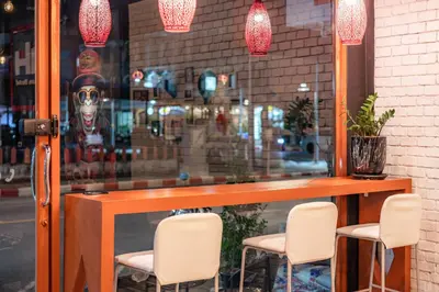 a table and chairs in front of a store window at The Dorm Hostel in Ban Lo Long