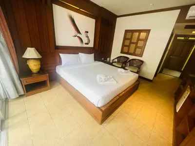 a bedroom with a bed and a table and a lamp at Talya Patong Hotel in Patong Beach