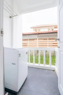 a kitchen with white appliances and a balcony at White House Apartment - Chalong in Chalong