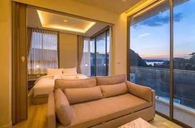 a bedroom with a couch and a bed and a large window at CORNER SEA VIEW KRABI Ao Nang 4 STARS HOTEL RESIDENCE in Ao Nang Beach