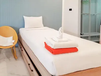 a bed with towels and a chair in a room at Kata Forte Resort in Kata Beach
