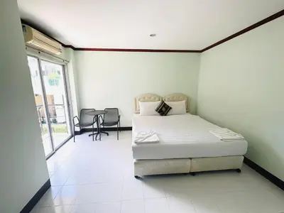 a bedroom with a bed and a table and chairs at Cocoon Omaya Guest House in Patong Beach