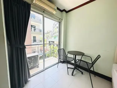 a room with a table and chairs and a large window at Cocoon Omaya Guest House in Patong Beach