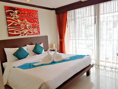 two swans sitting on a bed in a bedroom at Southern Comfort Patong in Patong Beach