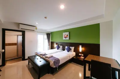 a bedroom with a large bed and a green wall at Ratana Hotel Sakdidet, PHUKET TOWN in Phuket Town