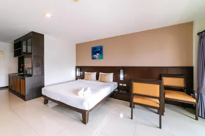 a bedroom with a bed and a table and a chair at Ratana Hotel Sakdidet, PHUKET TOWN in Phuket Town
