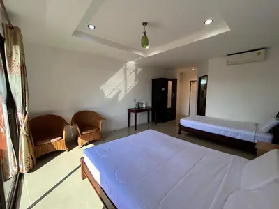 a bedroom with a bed and two chairs in it at Relaxation guesthouse in Thalang