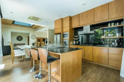 a kitchen with wooden cabinets and a bar with stools at Baan Bua BT17 by Villacarte in Nai Harn Beach