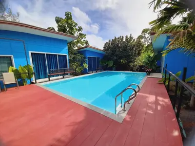 a swimming pool in front of a blue building at RadHut in Chalong