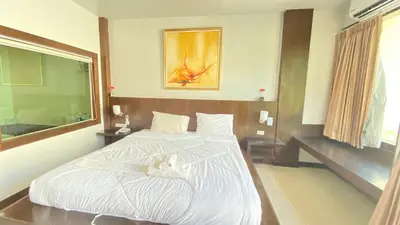 a bedroom with a white bed and a mirror at SM Patong Resort in Patong Beach