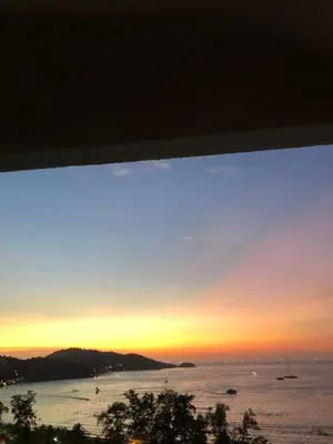 a sunset view from the balcony of a house at Patong Tower Ocean View Apartment in Patong Beach