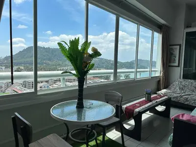 a table with a vase on it in a room with windows at Patong Tower Ocean View Apartment in Patong Beach