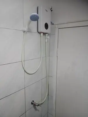 a shower with a hose attached to a wall at STPhostel in Patong Beach