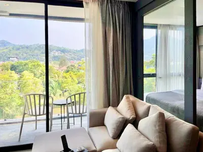 a living room with a couch and a large window at Kamala Beach P79 Exclusive Junior Suite in Kamala Beach