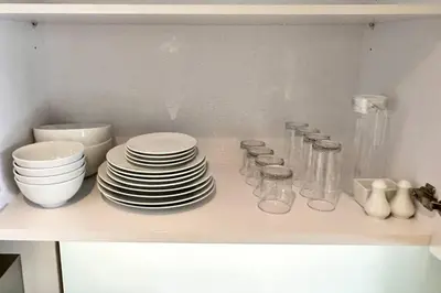 a shelf with plates and bowls and glasses on it at Daimond Exclusive Junior Suite Bangtau Beach in Bang Tao Beach