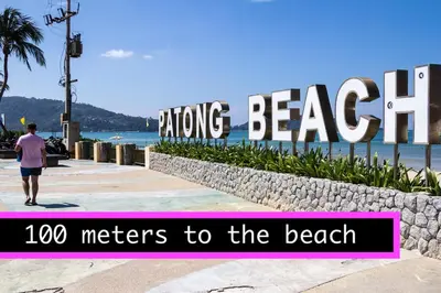 a man walking past the beach with the sign hugging the beach at Centre Point Patong in Patong Beach