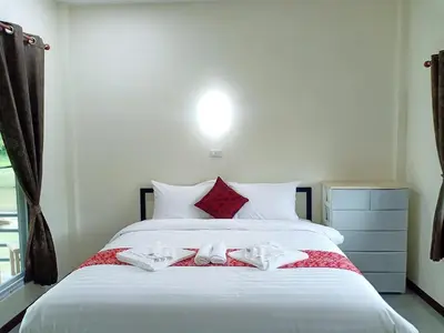 a bedroom with a large white bed with red pillows at Bang Yan Rimlay in Ko Yao Noi