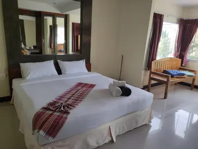 a bedroom with a large white bed with a teddy bear on it at Baan Thara Guesthouse in Ao Nang Beach