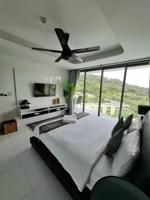 a bedroom with a large bed with a ceiling fan at Twin Sands Resort Penthouse in Patong Beach