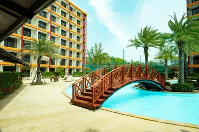 a wooden bridge over a swimming pool in a resort at 777 Beach Condo Phuket in Mai Khao Beach