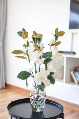 a glass vase with white flowers on a table at Sunset Residence Karon Beach in Karon Beach