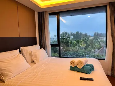 a bedroom with a bed with a large window at Aristo O59 Junior Suite Surin Beach in Phuket Town