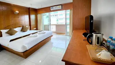 a bedroom with a bed and a desk with a television at Chalita House in Patong Beach