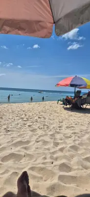 a persons foot in the sand on a beach with an umbrella at Mamatel boutique in Kamala Beach