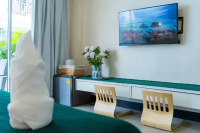 a room with a desk with two chairs and a vase of flowers at Patong Beach Side Hotel in Patong Beach
