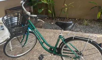 a green bike with a basket parked on a sidewalk at The Phuket Pool Villa in Phuket Town